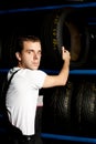 Young mechanic reaching tire in car service