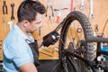 a young mechanic wearing gloves using chain lube lubricating the chain and freewheel