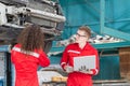 Young mechanics team in uniform are working in auto service with lifted vehicles. Car repair and maintenance concepts Royalty Free Stock Photo