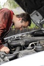 Young mechanist checking a car engine