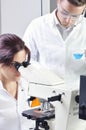 Young medical scientists studying new substance or virus in microscope