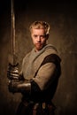 Young medieval knight posing on dark background. Royalty Free Stock Photo