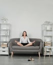 Young meditation businesswoman doing yoga exercise on sofa at workplace in a modern office. Employee feel balance