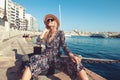 Young Mediterranean woman sitting at dock in Valletta, Malta