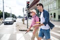 Young man and blind senior with white cane walking in city, crossing street.