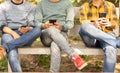 Young Men busy on mobile while sitting on table at park - Concept of young generation addicted to smartphone, technology