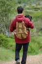 Young men carries a dog in a mountain path