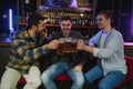 Young men in casual clothes are talking, laughing and drinking while sitting at bar counter in pub Royalty Free Stock Photo