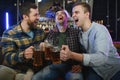 Young men in casual clothes are talking, laughing and drinking while sitting at bar counter in pub Royalty Free Stock Photo