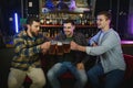 Young men in casual clothes are talking, laughing and drinking while sitting at bar counter in pub Royalty Free Stock Photo