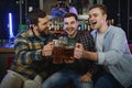 Young men in casual clothes are talking, laughing and drinking while sitting at bar counter in pub Royalty Free Stock Photo