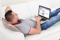 Man Chatting On Laptop While Lying On Sofa