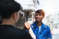 Young man client shaking hands with auto mechanic in red uniform having a deal at the car service Royalty Free Stock Photo