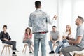 Young man in denim outfit speaking to a group of teenagers with Royalty Free Stock Photo