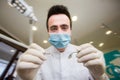 Young men dentist with sterile mask readily approaching a patient with dental instruments held in the hands protected with surgica Royalty Free Stock Photo