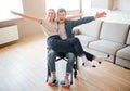 Young man with disability and inclusiveness holding girlfirend on knees. They smile and pose on camera. Cheerful happy Royalty Free Stock Photo