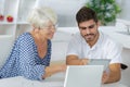 Young man and elderly lady looking at tablet screen