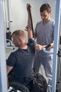 Young man exercises physio therapy. Doctor helps patient in wheelchair Royalty Free Stock Photo