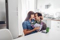 Young man gifting bouquet of flowers to his girlfriend in kitchen. Happy couple hugging. Romantic surprise Royalty Free Stock Photo