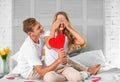 Young man giving red heart to his beloved girlfriend at home