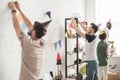 young men hanging up string with party garlands and their friends