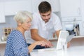 Young man helping lady with computer