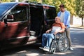 Young man helping patient in wheelchair to get into van Royalty Free Stock Photo