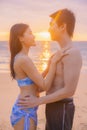 Young man and his girlfriend are looking into each other on a beach with a sea back and romantic sunset at Nai Thon Beach, Phuket