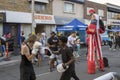 Young men imitate a boxing match and a man walking on stilts with boxing gloves on