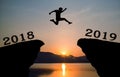 A young man jump between 2018 and 2019 years over the sun and through on the gap of hill silhouette