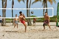 Young Men Kick A Soccer Ball On Beach Volleyball Court