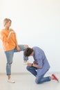 Young man is kneeling and reverently tying shoelaces to his domineering unidentified woman posing on a white background Royalty Free Stock Photo