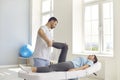 Young man osteopath checking joints of lying woman patients legs