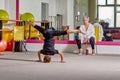 A young man performs tricks under the supervision of a teacher.