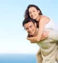 Taking her to see the view. A young man piggybacking his girlfriend with a view of the ocean in the background. Royalty Free Stock Photo