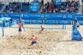 Young men playing professional beach volleyball match in outdoor arena
