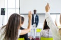 Young man raising hand to ask question. Boss leader businessman presenting new project to multiracial colleagues during briefing.