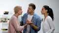 Young man settling conflict between mother and wife, family problems, quarrel