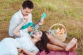 Young man sitting on picnic blanket with his girlfriend and playing guitar Royalty Free Stock Photo