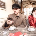 Young man with smartphone at the bar. Blurry of beautiful crying brunette girl. Loving couple who are quarreling. On the table are