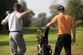 Young men standing in golf course by golf bag full of sticks Royalty Free Stock Photo