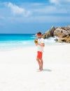 Young men in swim short with a coconut drink on a tropical beach La Digue Seychelles Islands Royalty Free Stock Photo