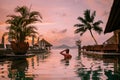 Young men in swimming pool during sunset, Luxury swimming pool in tropical resort, relaxing holidays in Seychelles