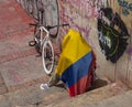 A young men take cover of midday sun with colombian flag and its bicycle during paro nacional marches
