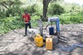 Young men using hand pump at community water well to collect drinking water, Tanzania, Africa