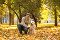 A young men walks in autumn park with a Labrador. The guy squa Royalty Free Stock Photo