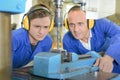 Young man watching engineer use bench drill Royalty Free Stock Photo