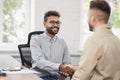 Young men wearing smart casual clothes shaking hands while working. Handshake in creative office. Business lifestyle