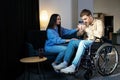 Young man in a wheelchair. Girlfriend comforting her sad boyfriend