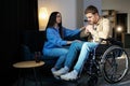 Young man in a wheelchair. Girlfriend comforting her sad boyfriend